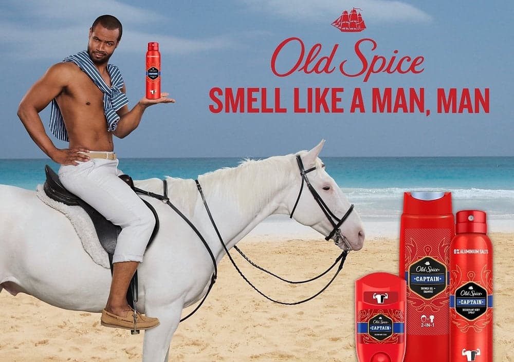 Image 3: Un vibrante anuncio de Old Spice protagonizado por Isaiah Mustafa, que sostiene un producto Old Spice sentado con confianza en un caballo blanco en la playa. El eslogan 